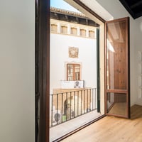 Spacious balcony with ocean view from a modern apartment. Minimalist design, glass railing, elegant outdoor furniture.