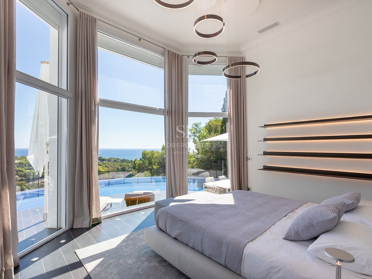 Modern master bedroom with floor-to-ceiling windows overlooking an infinity pool and the Mediterranean sea.