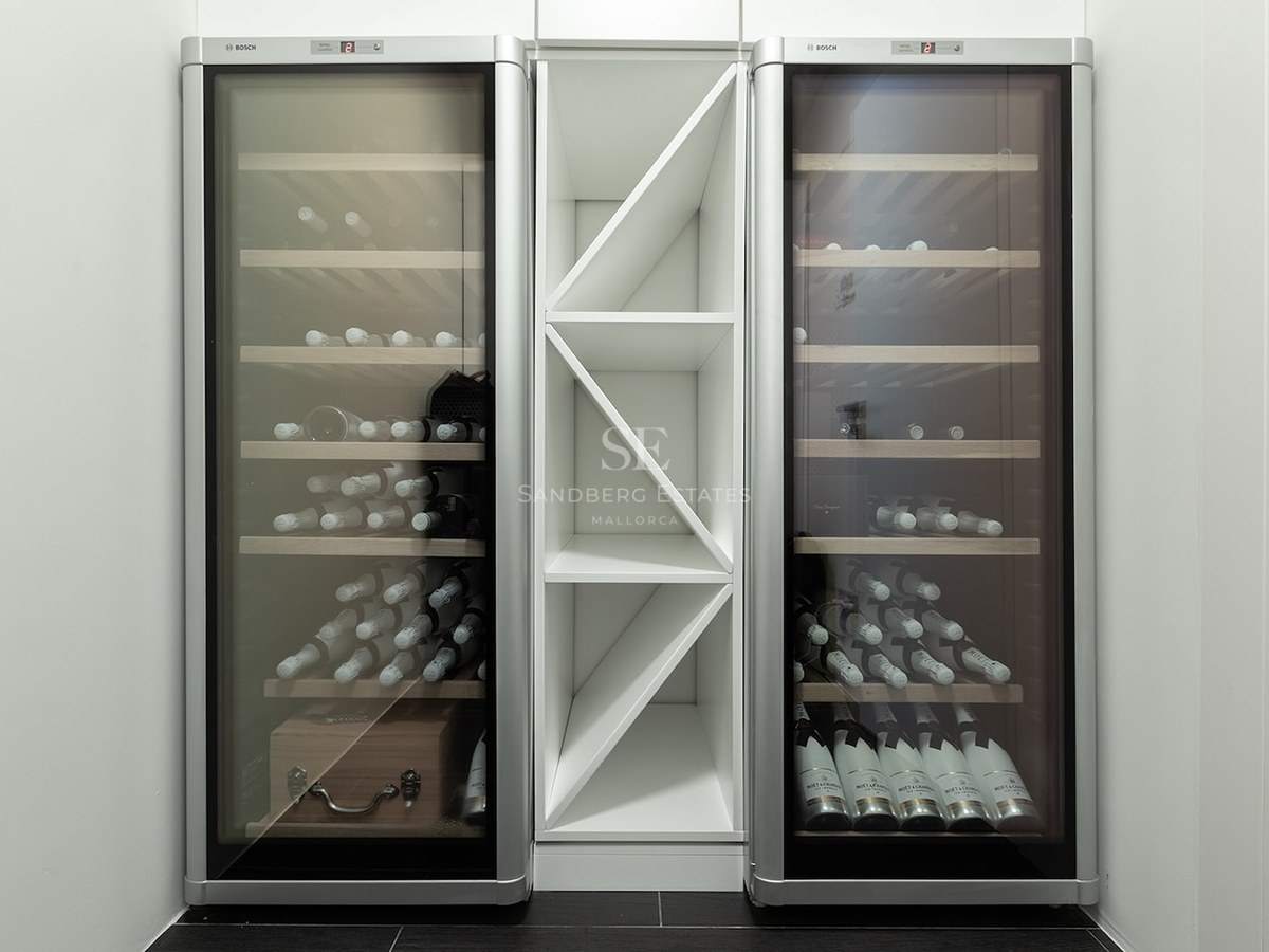 Two sleek silver Bosch wine fridges flanking a central white geometric bottle rack in a minimalist interior.