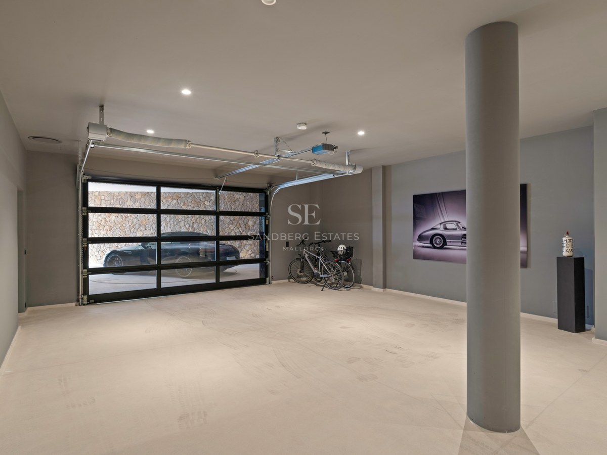Rymligt modernt underjordiskt garage med sektionsdörr i glas, polerat betonggolv och infälld belysning.