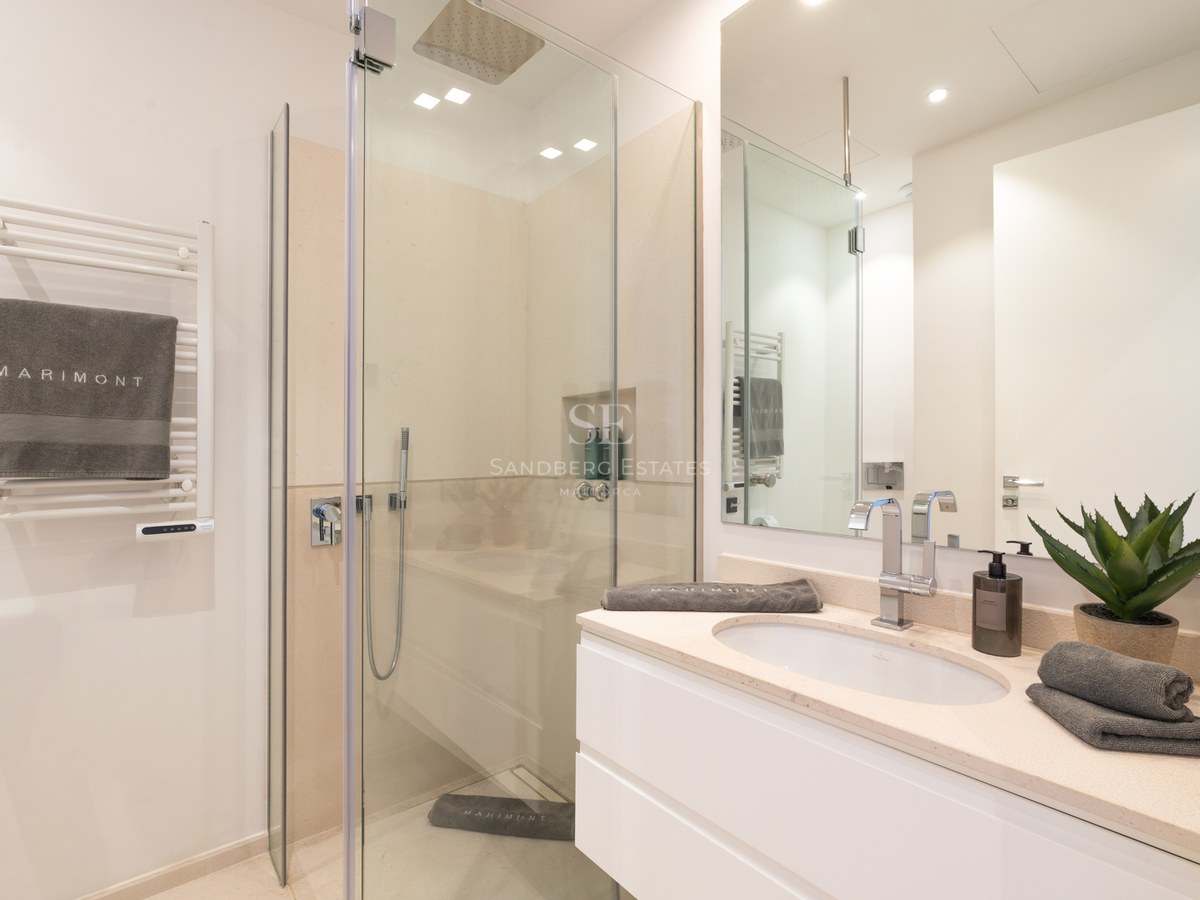 Modern bathroom featuring a glass walk-in shower, white vanity with chrome faucet, and a heated towel rack.