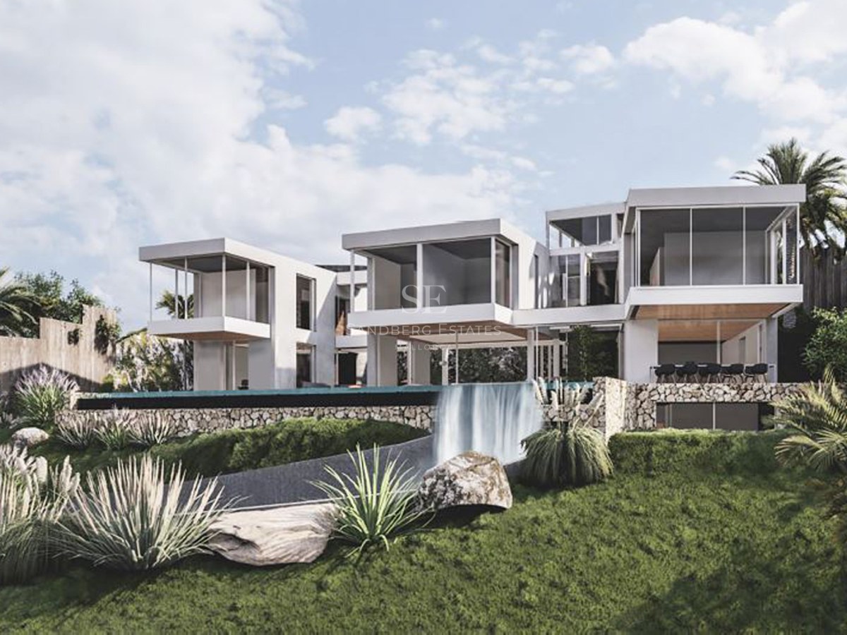 Modern white multi-level villa with cantilevered rooms and an infinity pool waterfall spilling into a landscaped garden.