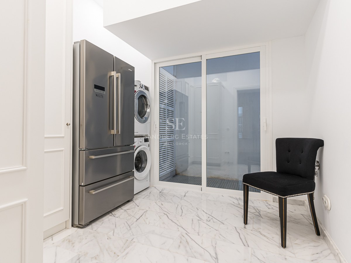 Utility room featuring a stainless steel refrigerator, stacked laundry unit, and white marble flooring.