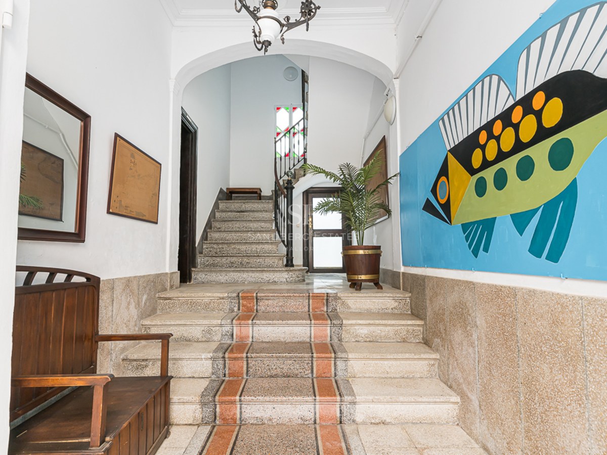 Entrance with stone stairs, wooden bench, and a large colorful fish mural on the wall.