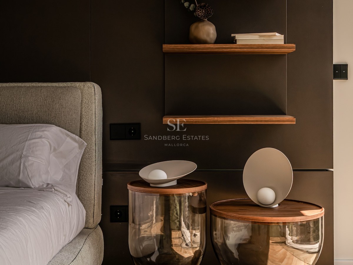 Modern bedroom corner featuring designer glass nightstands, floating walnut shelves, and herringbone oak flooring.