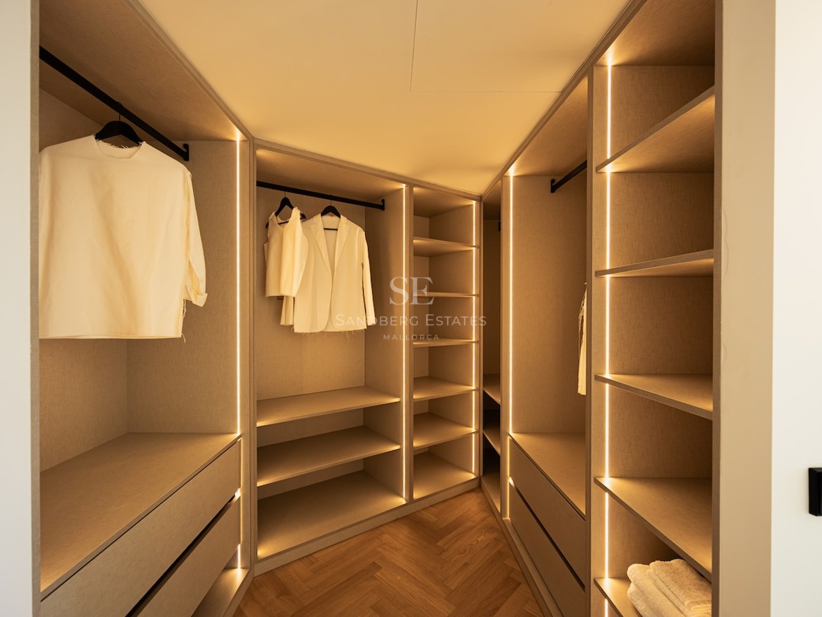 Dressing spacieux avec étagères en bois clair, éclairage LED intégré et parquet en chevrons.
