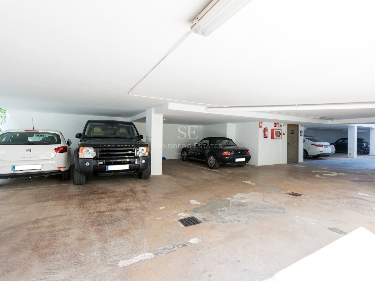 Bright underground parking garage with luxury vehicles parked in spacious designated bays.
