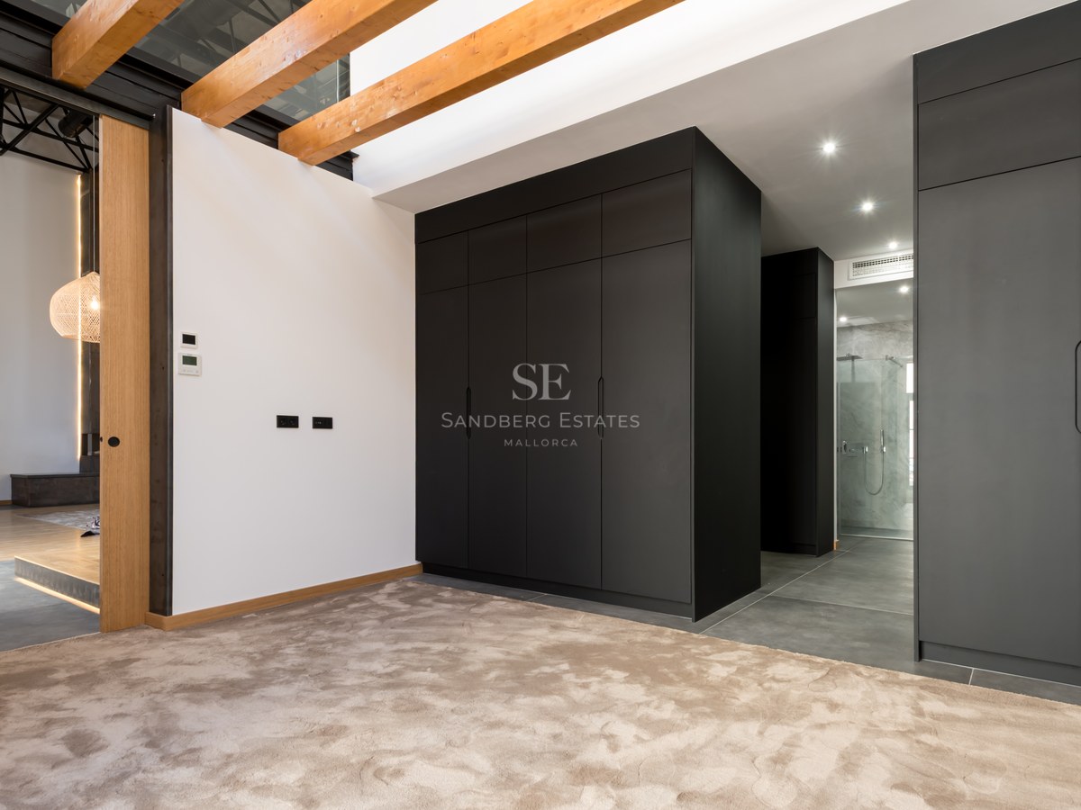 Dressing area featuring large black cabinets, exposed wooden ceiling beams, and plush beige carpeting.