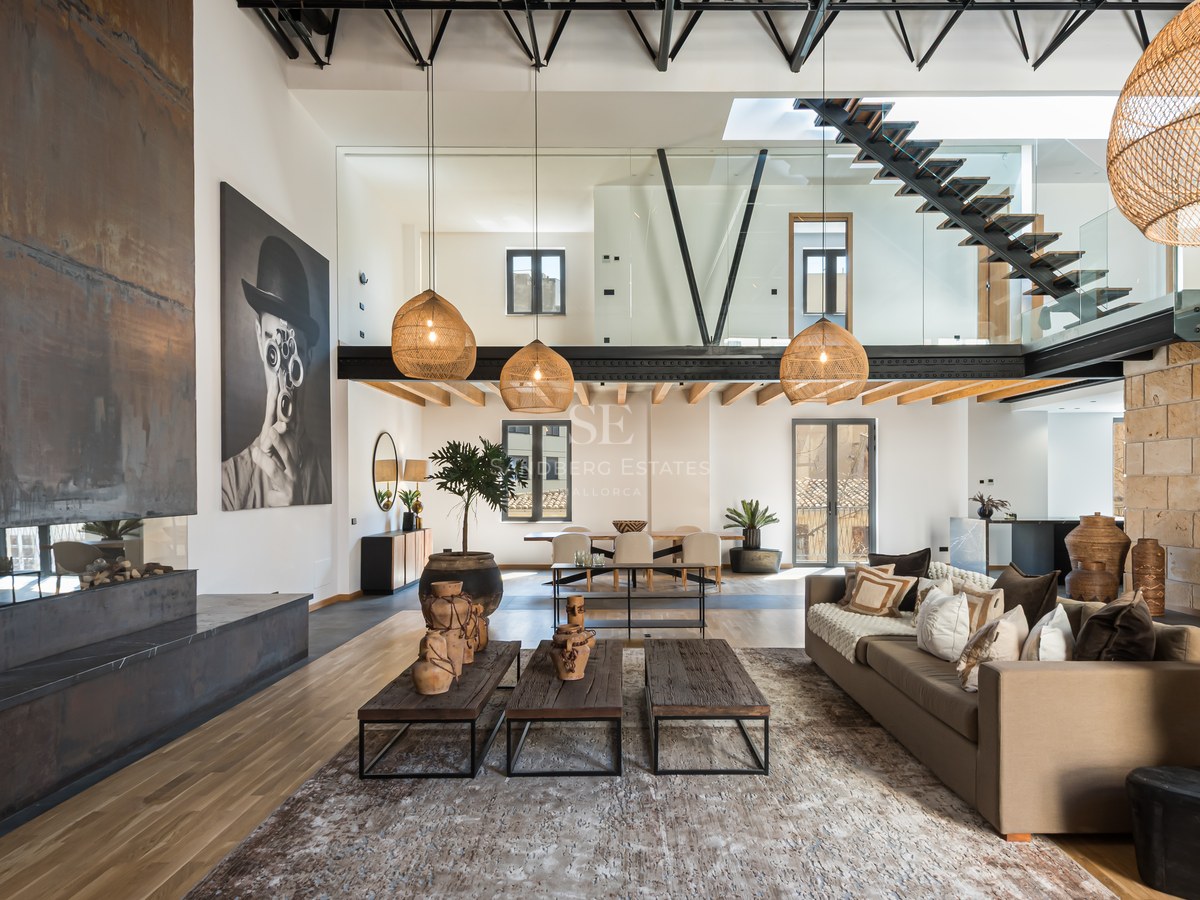 Spacious modern living room with a steel fireplace, high ceilings, floating staircase, and designer decor.
