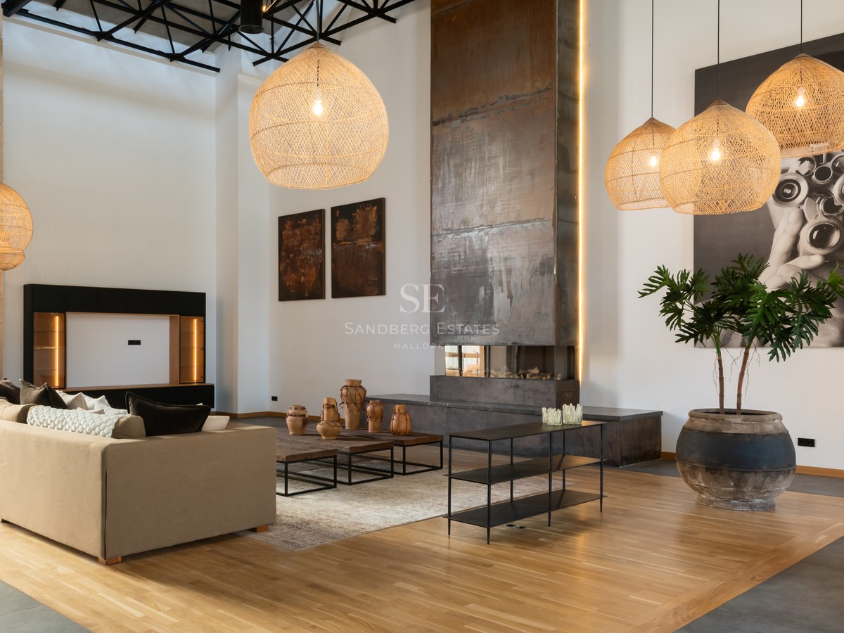 Spacious living room with high ceilings, large metal fireplace, wicker pendant lights, and modern beige sofa.