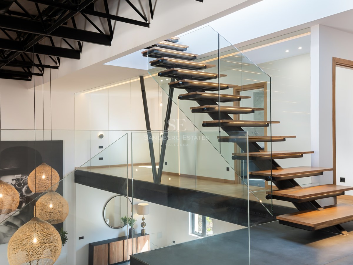 Wood and glass staircase with black metal structure and woven pendant lights in a modern interior.