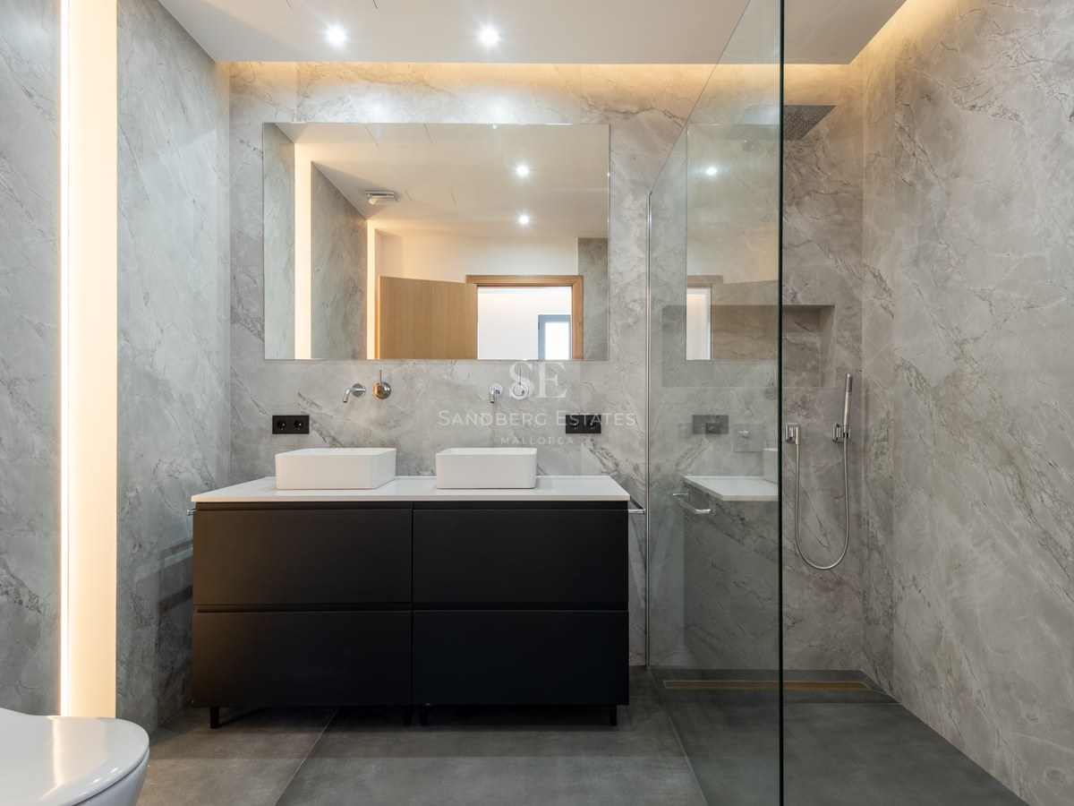 Elegant bathroom with gray marble walls, black double vanity, and glass walk-in shower.