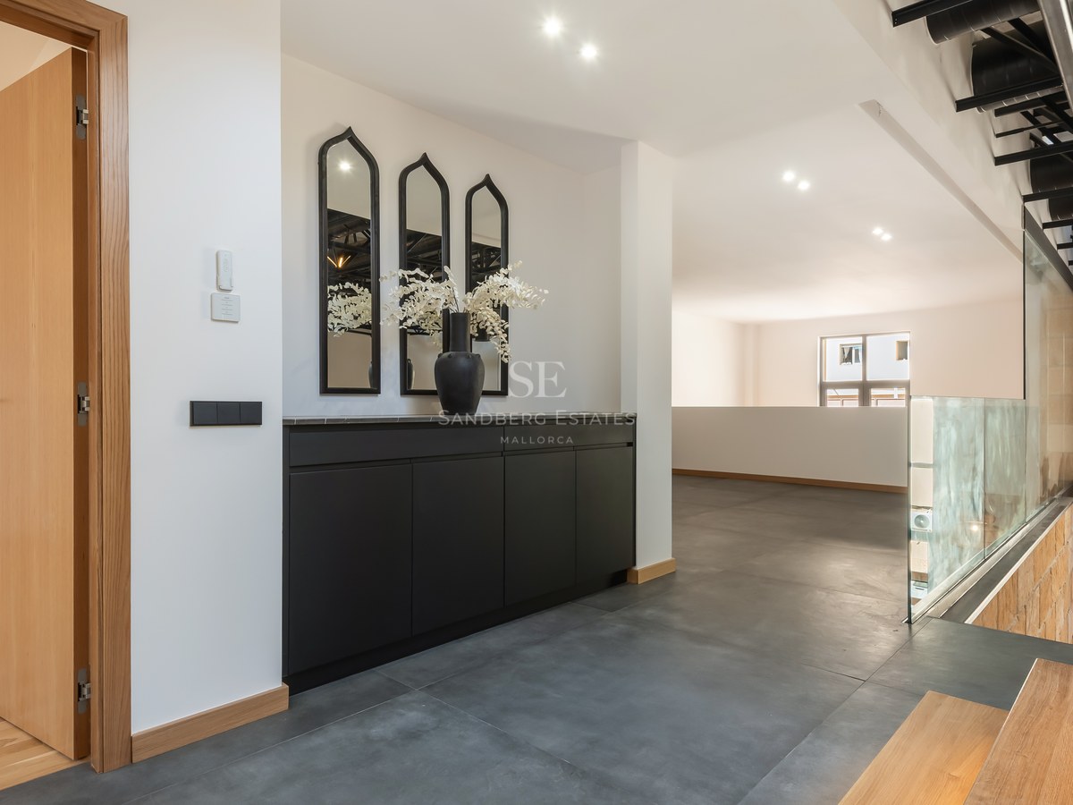 Modern hallway with black cabinetry, arched mirrors, grey tile floors, and a glass railing overlooking the lower floor.