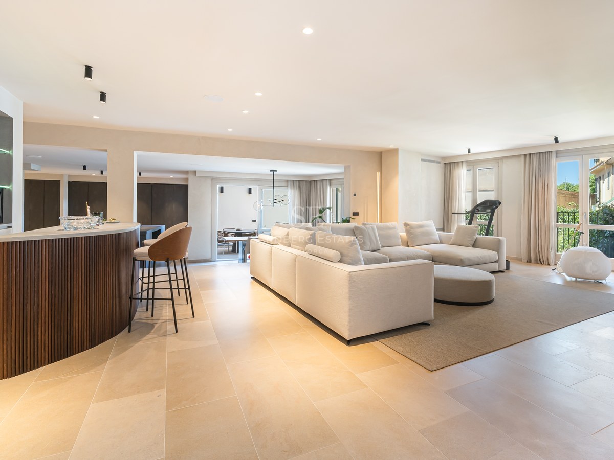 Spacious modern living room with a large white sofa, wooden bar counter, and natural stone flooring.