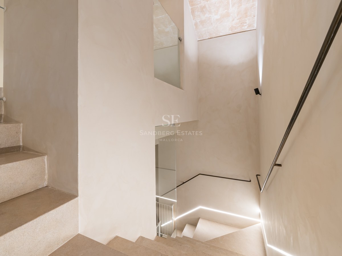 Minimalist design stone staircase with a slim metal handrail and integrated LED floor lighting.