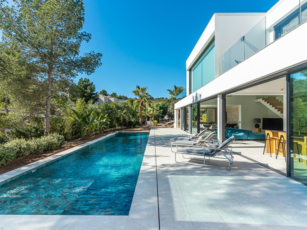 Utsikt över en modern pool med solstolar och parasoller. Ren och minimalistisk arkitektur, omgiven av grönska.