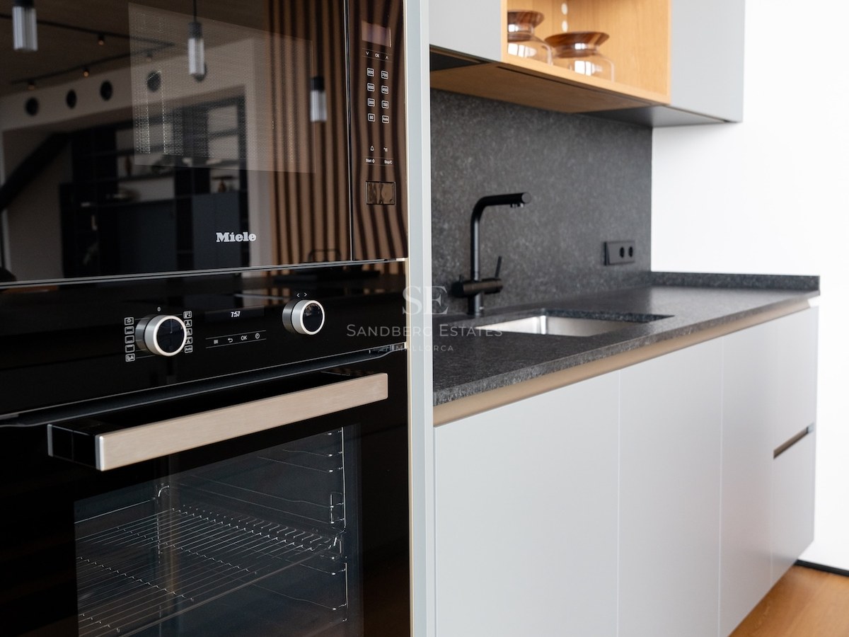 Nahaufnahme einer modernen Küche mit schwarzem Miele-Backofen, Granit-Arbeitsplatten und hellgrauen Schränken.