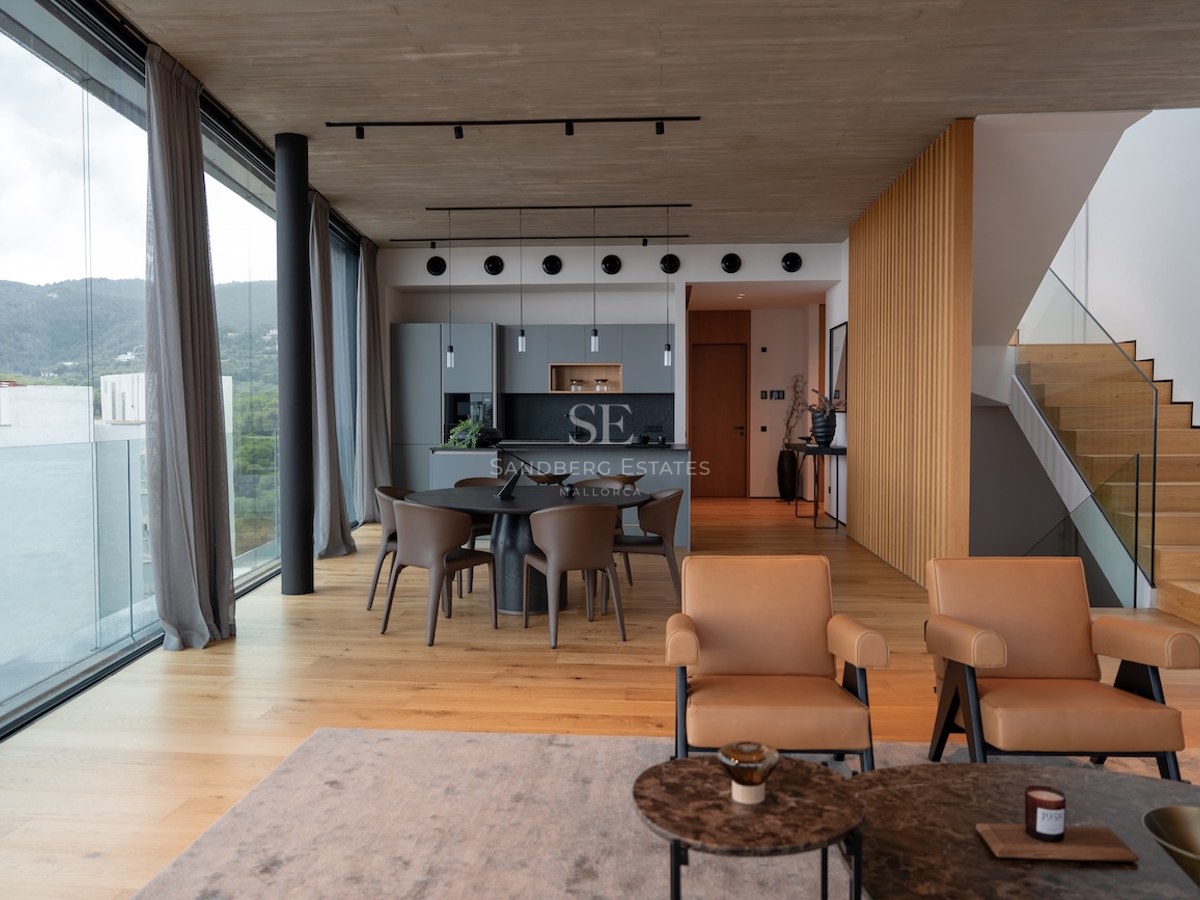 Bright open-concept living room with floor-to-ceiling windows, oak floors, concrete ceiling, and mountain views.