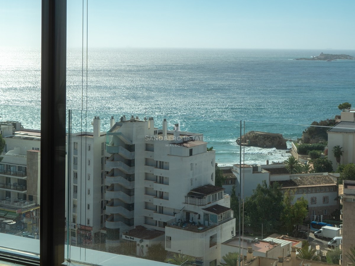 View of the Mediterranean Sea from a modern balcony with glass railings and coastal buildings in the foreground.