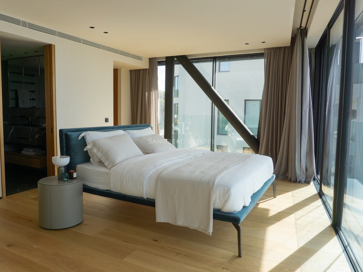 Contemporary bedroom featuring a blue fabric bed, oak flooring, and large glass walls with views.