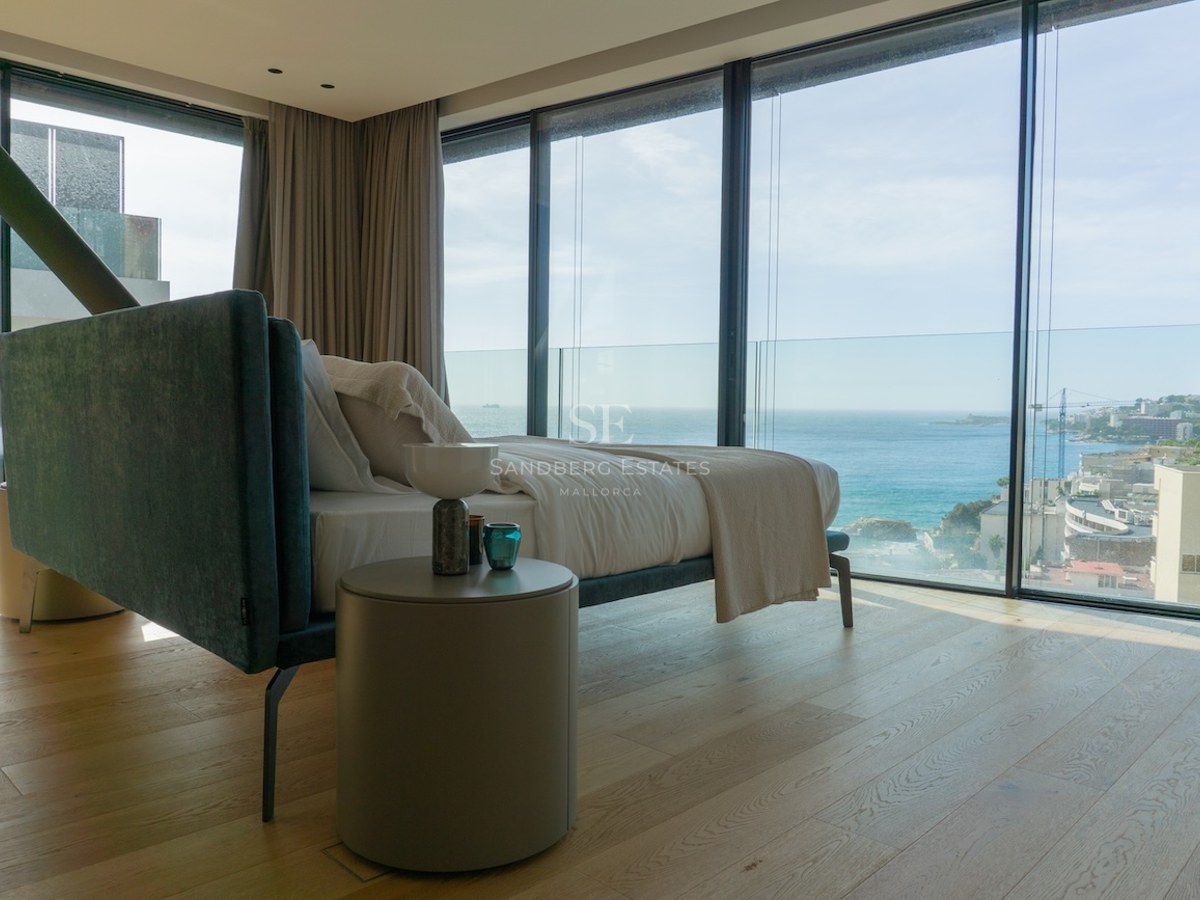 Modernes Schlafzimmer mit Eichenparkett und bodentiefen Glasfenstern mit Blick auf das Mittelmeer und die Küste.