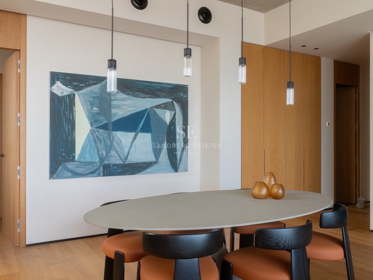 Modernes Esszimmer mit ovalem grauem Tisch, orangefarbenen Lederstühlen und abstrakter blauer Wandkunst.