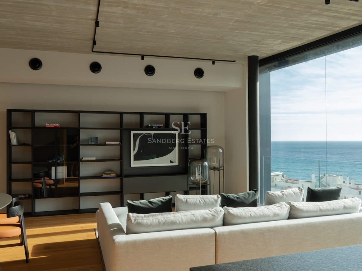 Contemporary living room featuring floor-to-ceiling windows with Mediterranean sea views, white sofa, and wooden floors.
