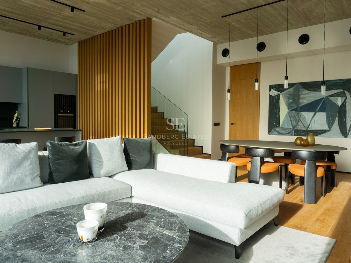 Modernes Wohnzimmer mit grauem Sofa, Marmortisch, Eichenparkett und Essbereich unter Sichtbetondecke.