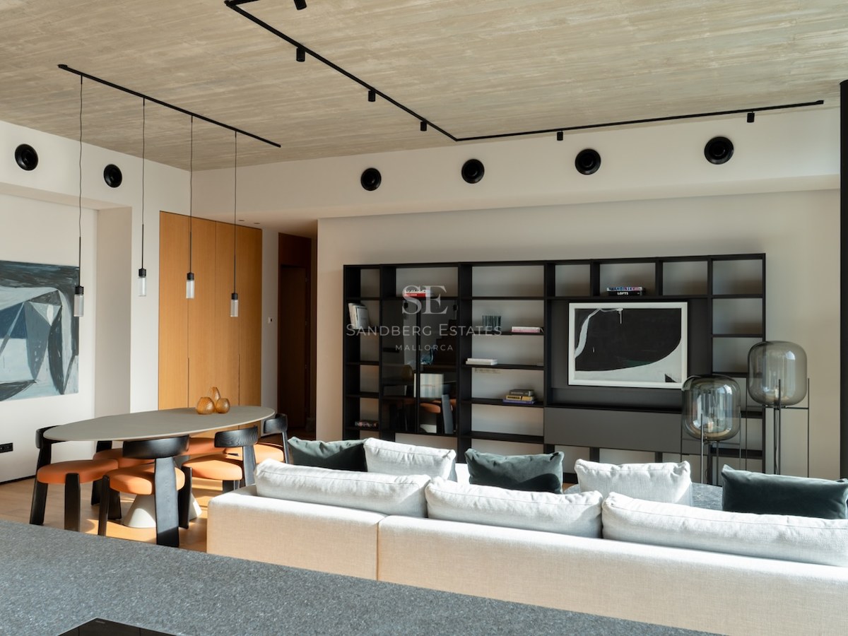 Modernes Wohnzimmer mit Beton-Decke, weißem Sofa, Essbereich und schwarzem Designer-Regal.