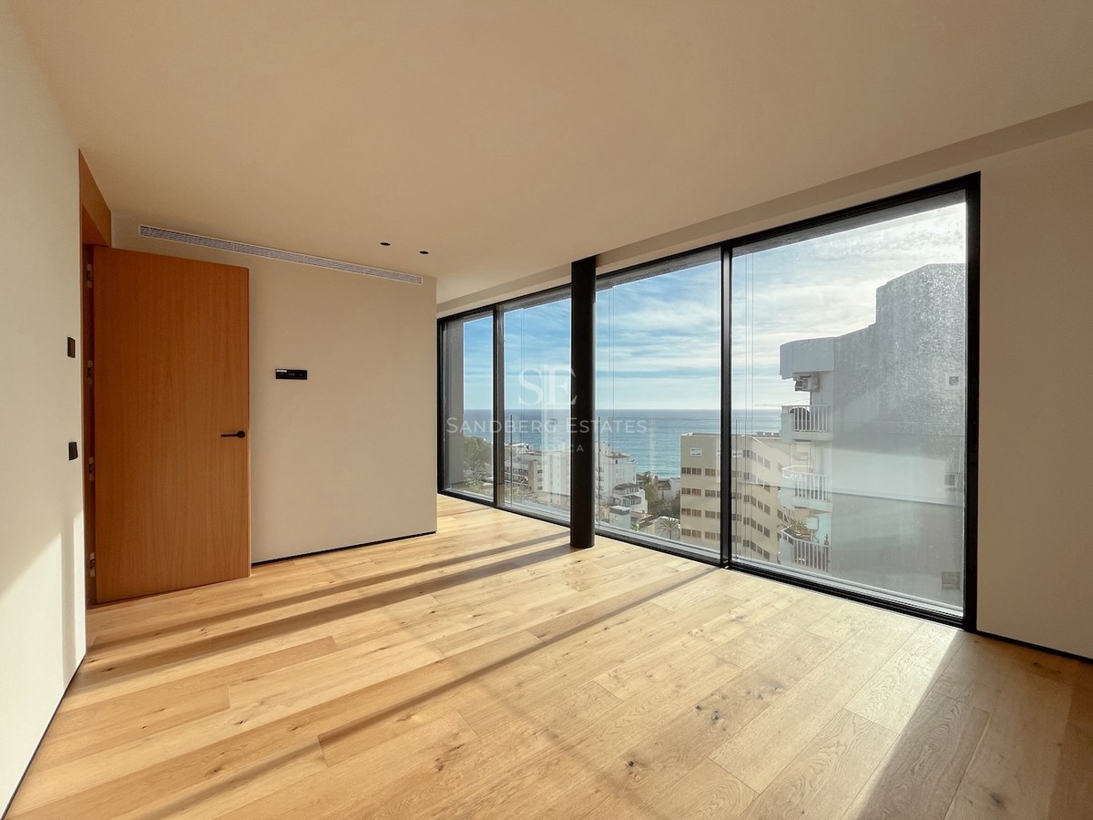 Leeres modernes Schlafzimmer mit Eichenboden und großen Fensterfronten mit Blick auf das Mittelmeer.