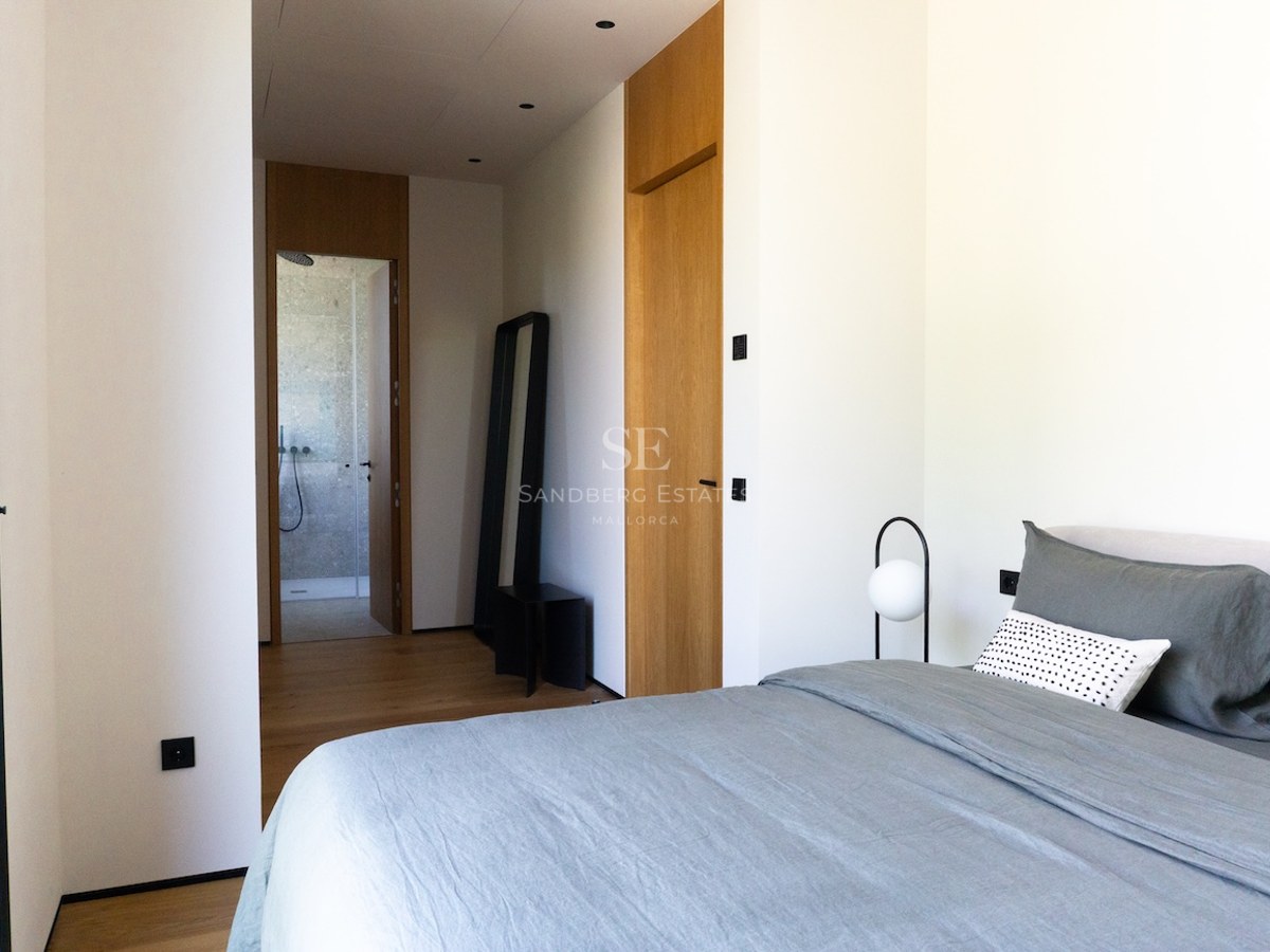 Helles minimalistisches Schlafzimmer mit Leinenbettwäsche, Eichenparkett und Blick in ein Naturstein-Bad.