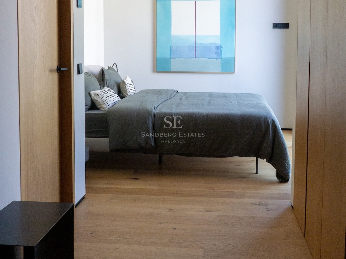 Zeitgenössisches Schlafzimmer mit salbeigrüner Leinenbettwäsche, Eichenholzböden und Einbauschränken.