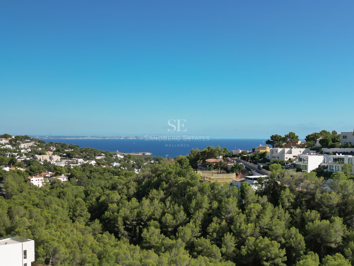 Spacious balcony with panoramic sea views. Glass railing, wooden floor and elegant outdoor furniture.