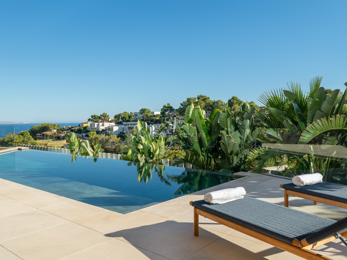 Spacious outdoor area with pool, manicured lawn, sun loungers, and lush vegetation. Ideal for relaxation and entertainment.