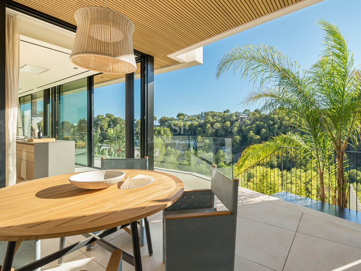 View of a modern infinity pool, surrounded by a wooden deck and lush greenery. Minimalist architecture and natural light.