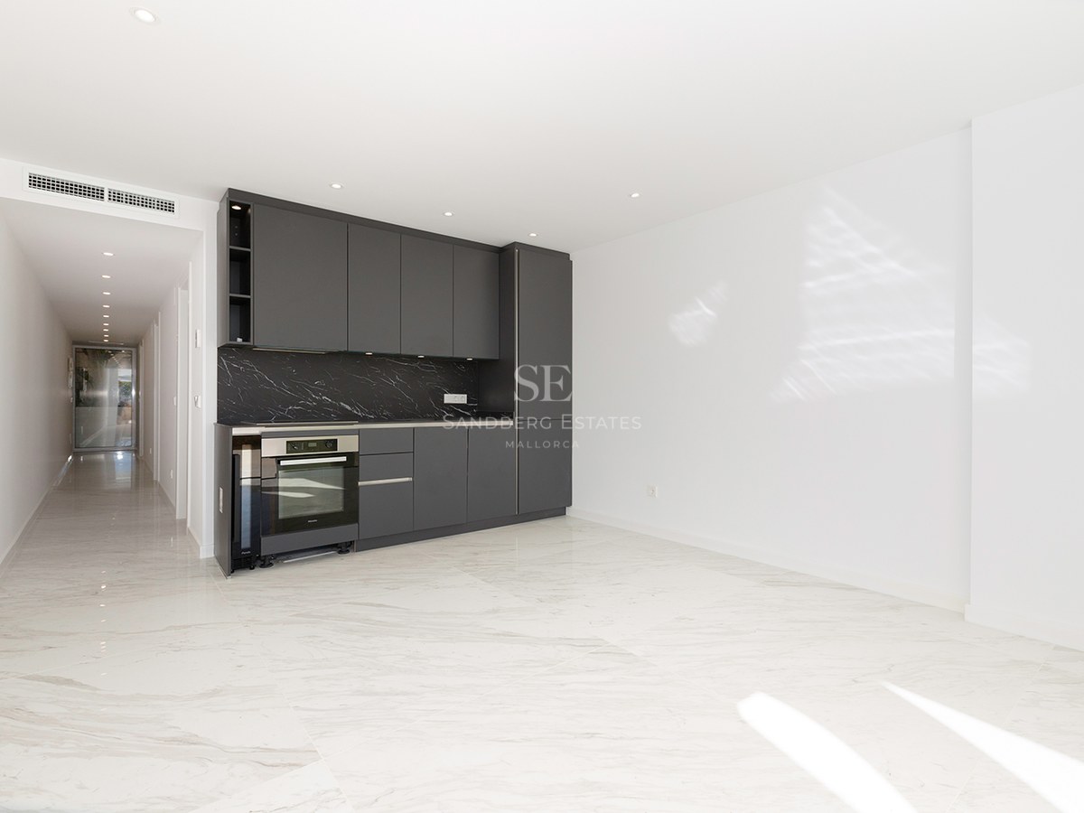 Modern kitchen area with dark gray cabinets, black marble backsplash, and white marble floors in a bright open room.