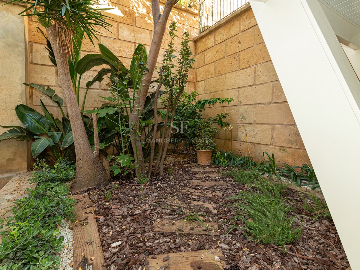 Natural stone wall with tropical plants and wood mulch in a private courtyard.