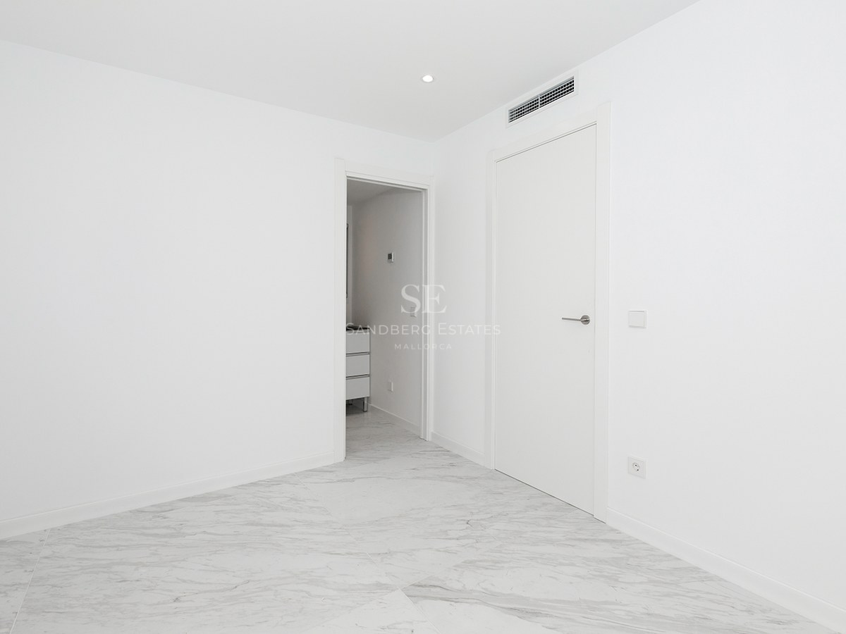 Bright empty room with white walls, polished grey-veined marble floors, and modern white doors.