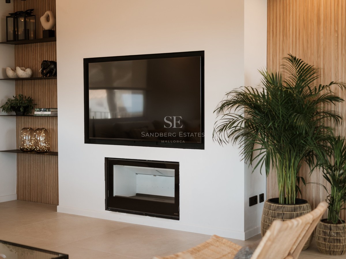 Pared blanca con televisión de pantalla plana sobre una chimenea minimalista integrada y paneles de madera de roble.