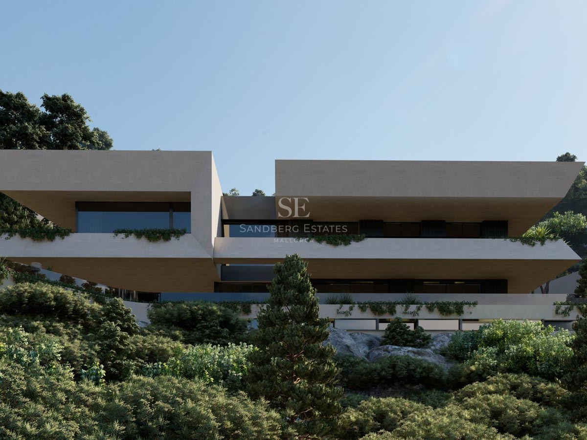 Villa moderna de dos niveles con volúmenes de piedra beige en voladizo integrada en una ladera verde bajo un cielo azul.