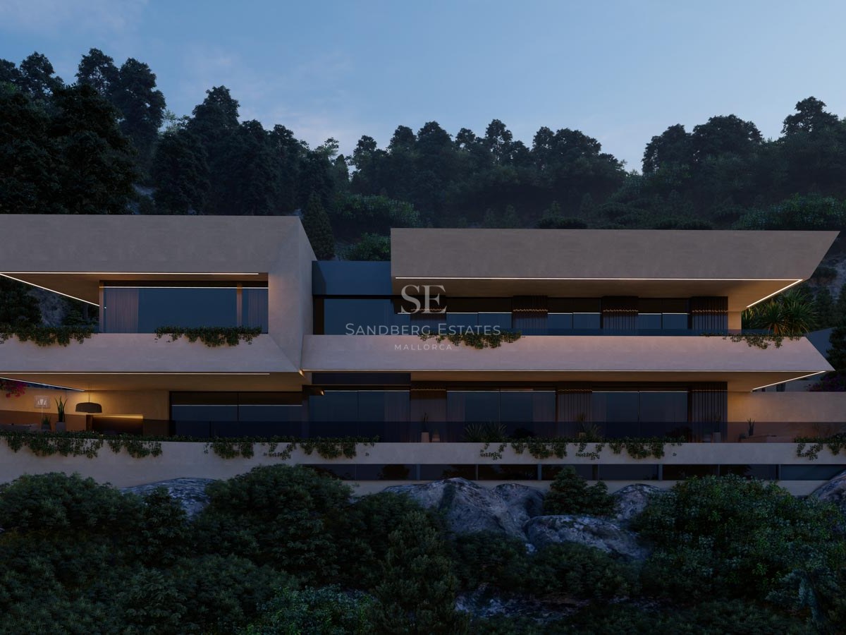 Vista nocturna de una villa moderna de varios niveles con voladizos, iluminación LED y vegetación en una ladera rocosa.