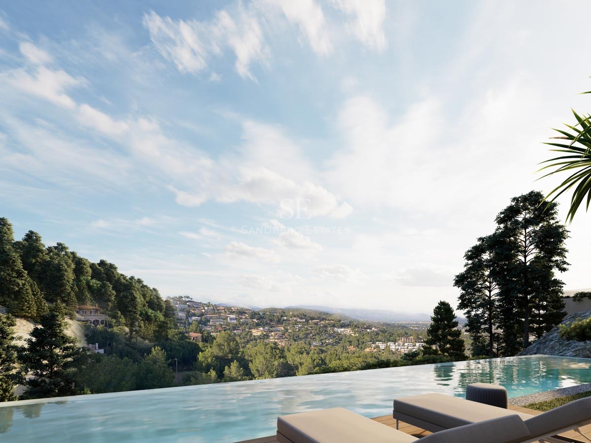 Piscina infinita de lujo con vistas a un valle verde y montañas bajo un cielo azul con tumbonas en primer plano.