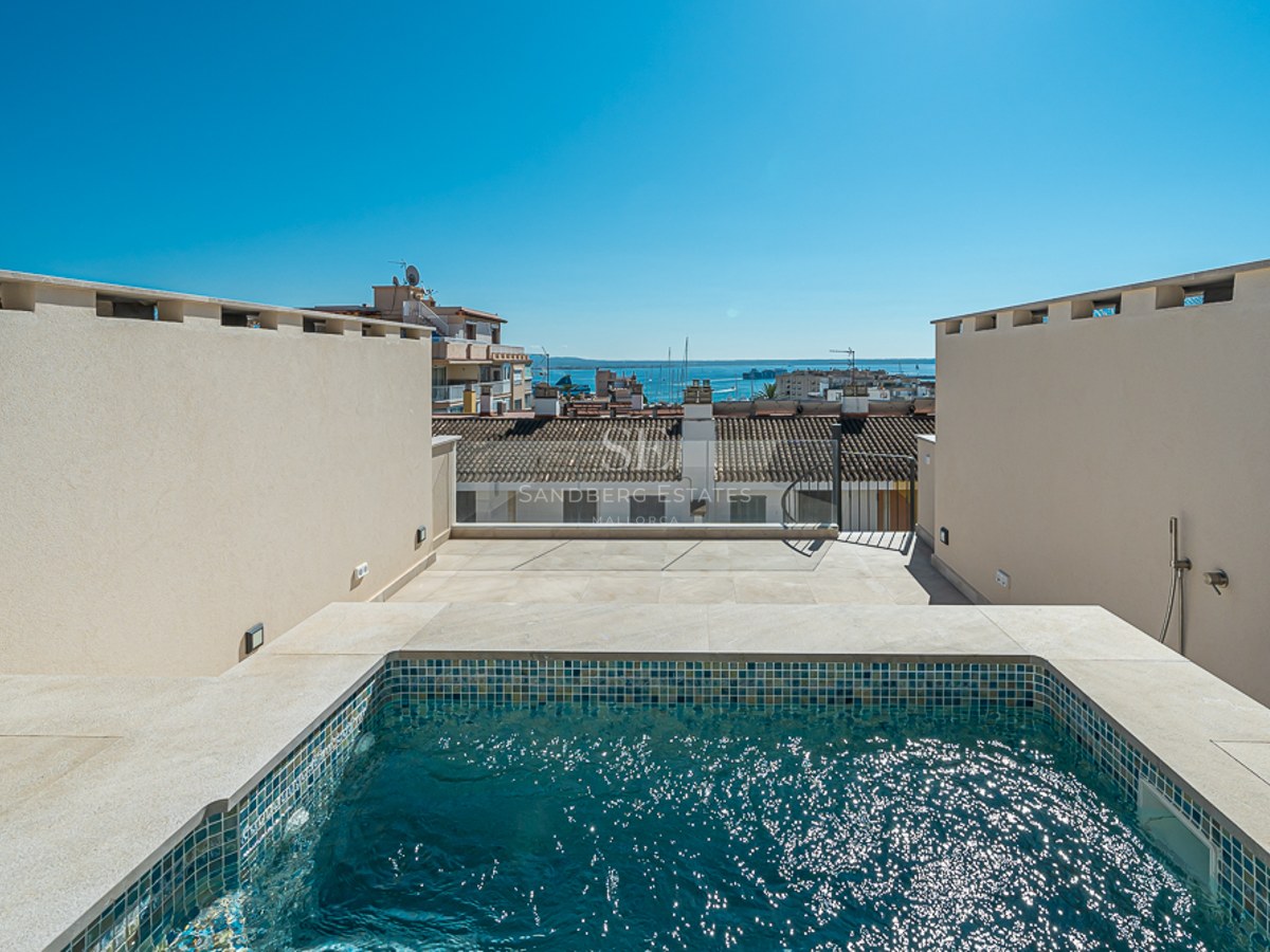Piscina privada tipo plunge en una azotea con azulejos de mosaico azul y vistas panorámicas al puerto y la ciudad.