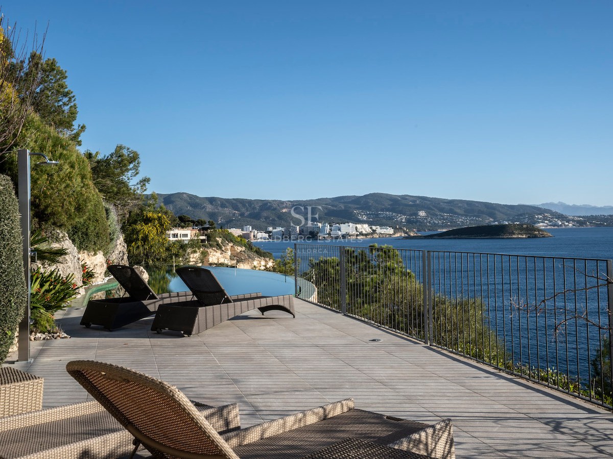 Luxury sun terrace with wicker loungers, infinity pool, and panoramic Mediterranean sea and mountain views.