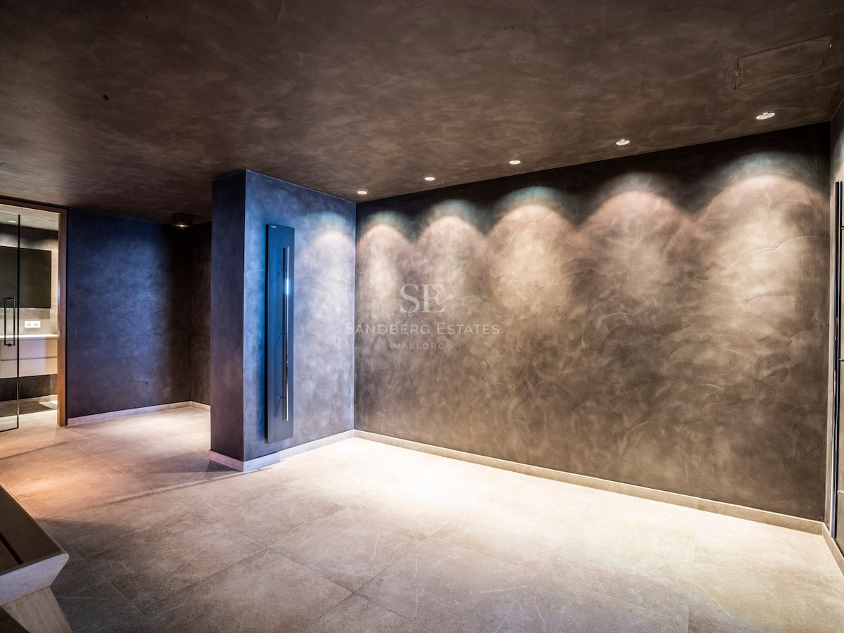 Minimalist spa area with dark textured plaster walls, recessed spotlighting, and light stone floor tiles.