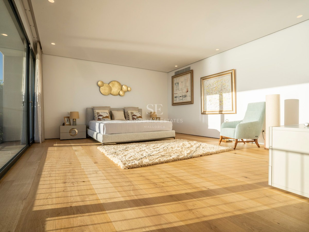 Bright modern master bedroom featuring oak floors, floor-to-ceiling glass doors, and contemporary furniture.