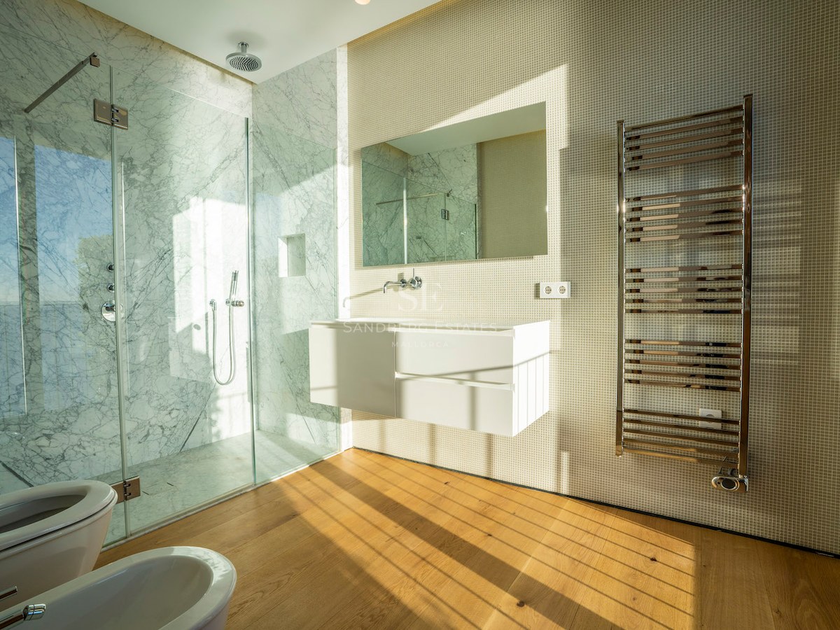 Contemporary bathroom featuring a glass walk-in shower with marble walls, floating white vanity, and oak flooring.