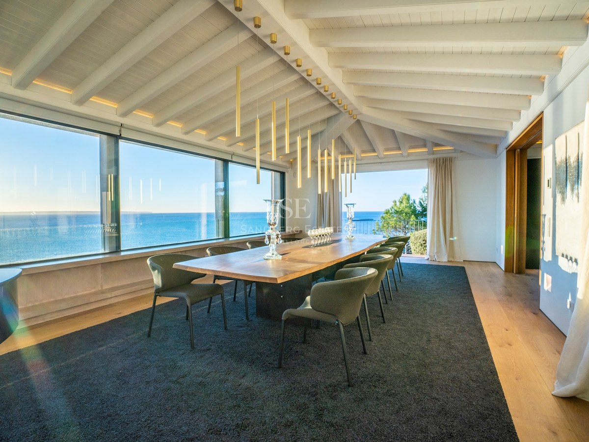 Luxury dining room featuring a solid wood table, designer seating, and expansive windows overlooking the Mediterranean Sea.