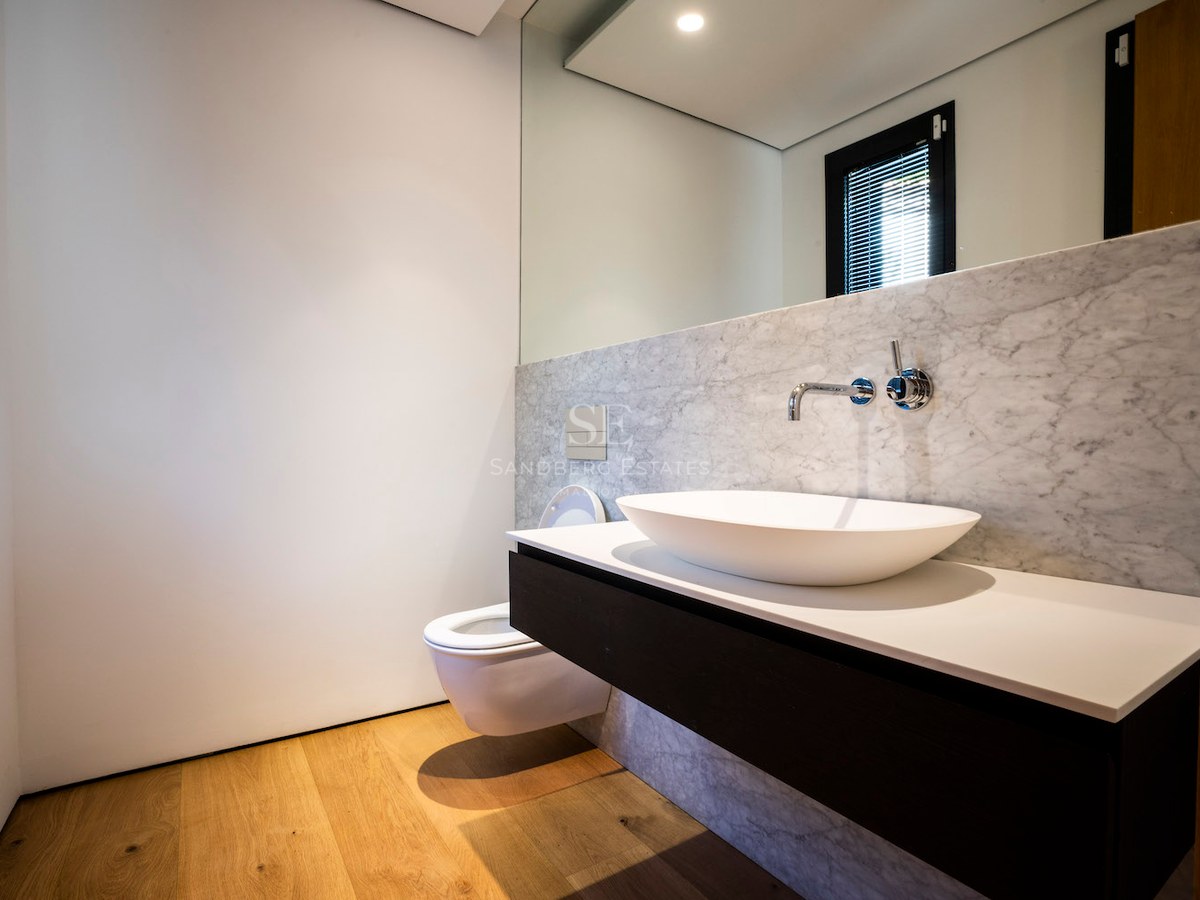 Contemporary bathroom featuring a white vessel sink on a floating vanity, stone wall tiles, and wooden flooring.