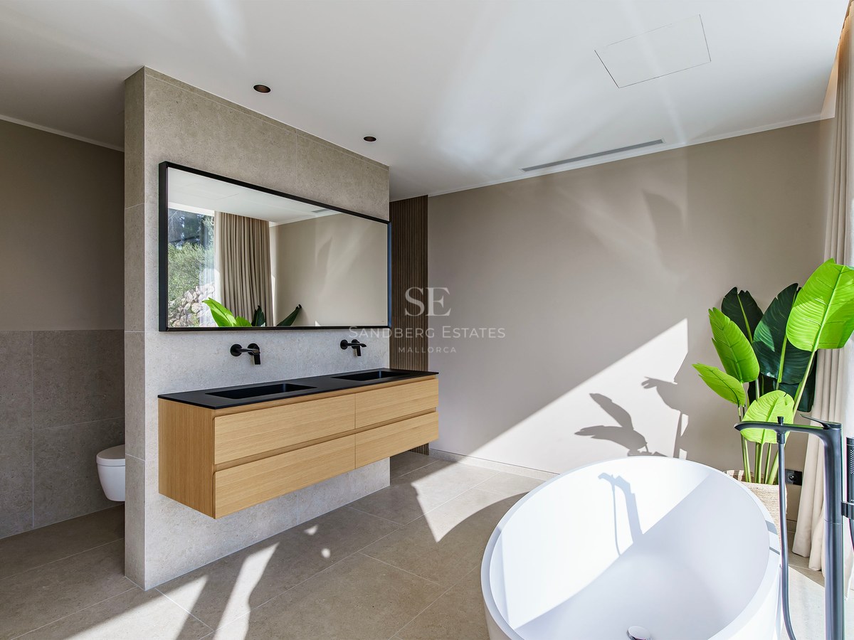 Salle de bain principale spacieuse avec baignoire blanche, double vasque suspendue en bois et robinetterie noire.